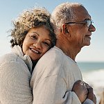 A senior woman embracing her husband by the beach