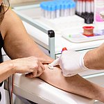 Cotton swab pressed onto a woman’s arm after blood collection.