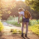 Woman on a hike in the forest applying insect repellent as mosquitoes swarm around her.